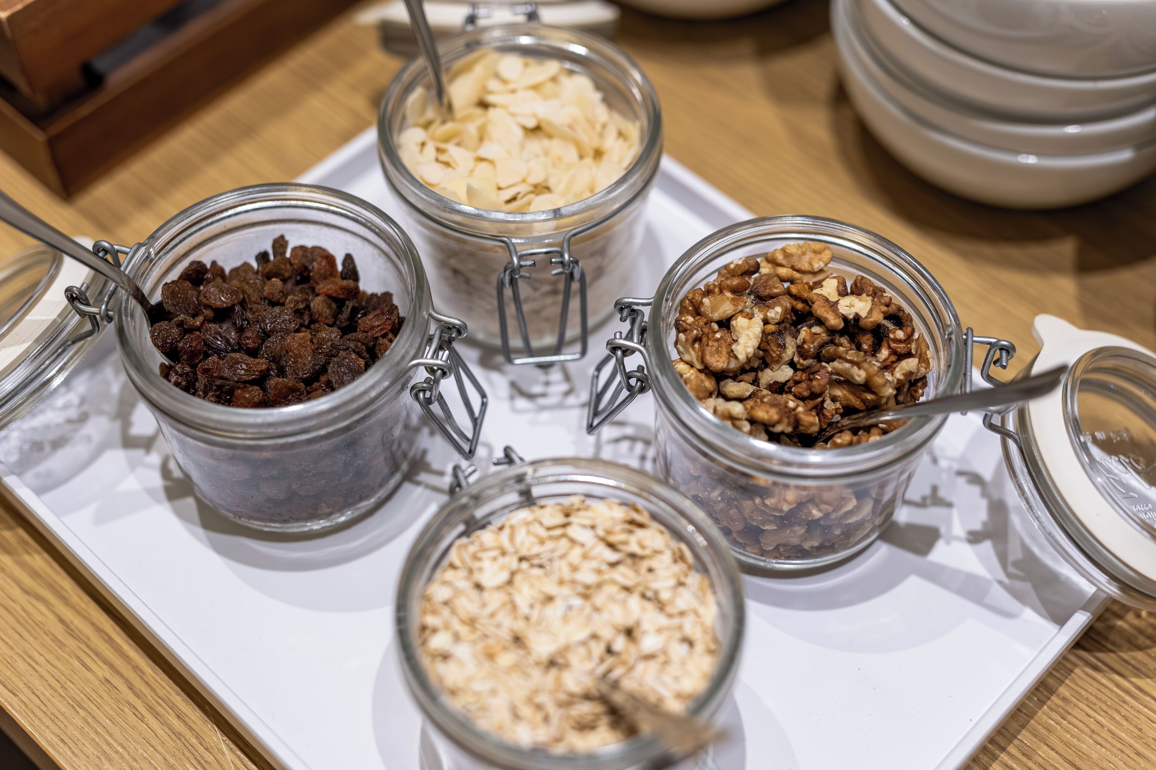 A tray with four glass jars containing different food items.
