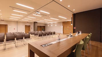 A conference room with a long table, chairs, and a projector screen.