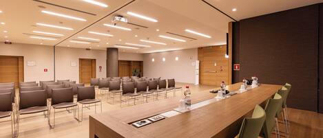 A conference room with a long table, chairs, and a projector screen.