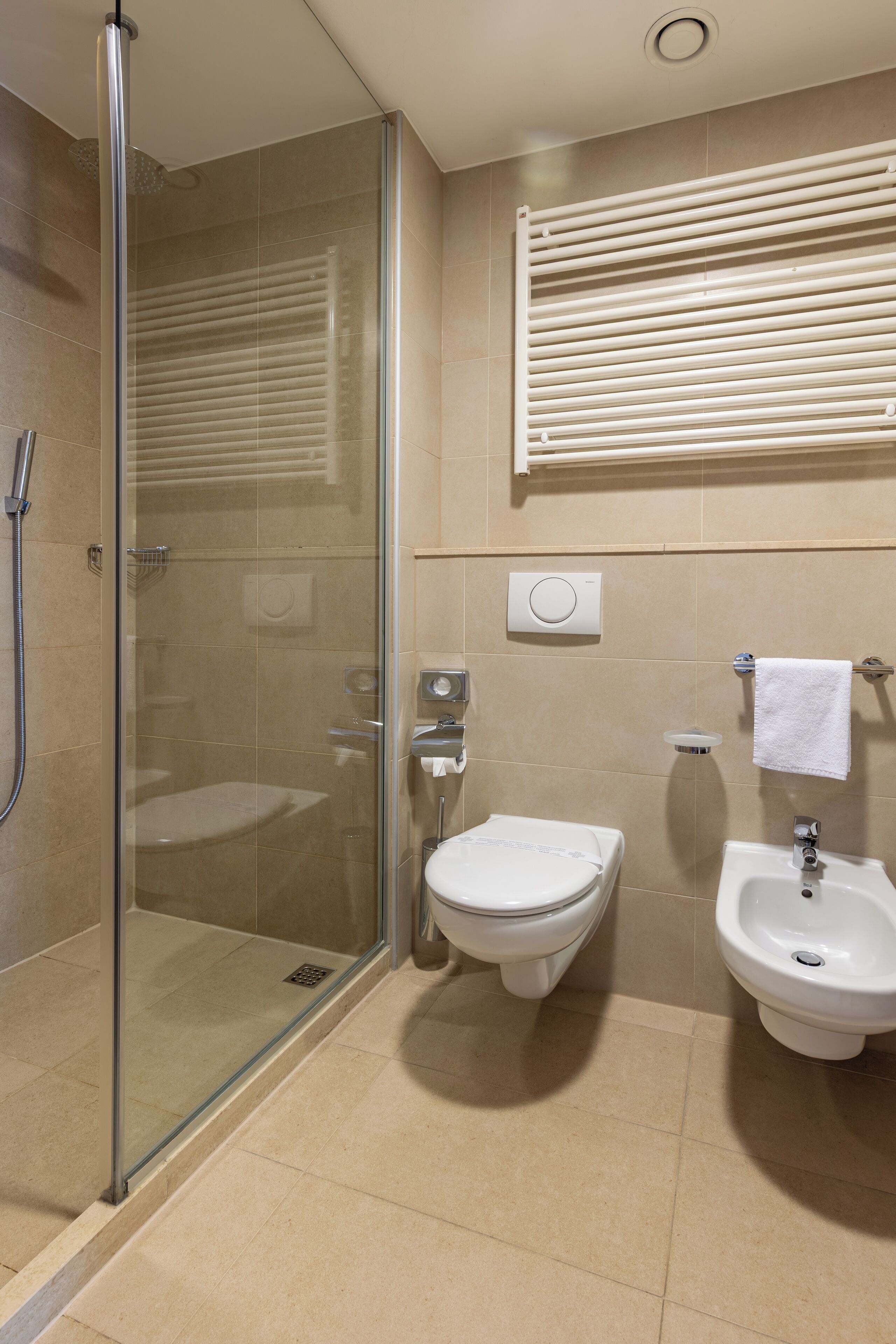 A modern bathroom with a glass-enclosed shower, a toilet, and a pedestal sink.