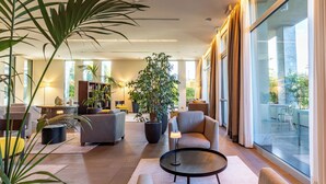 A spacious living area with sofas, a coffee table, and large windows offering a view of the outdoors. - HSM Hotel San Martino (Garbagnate Monastero)