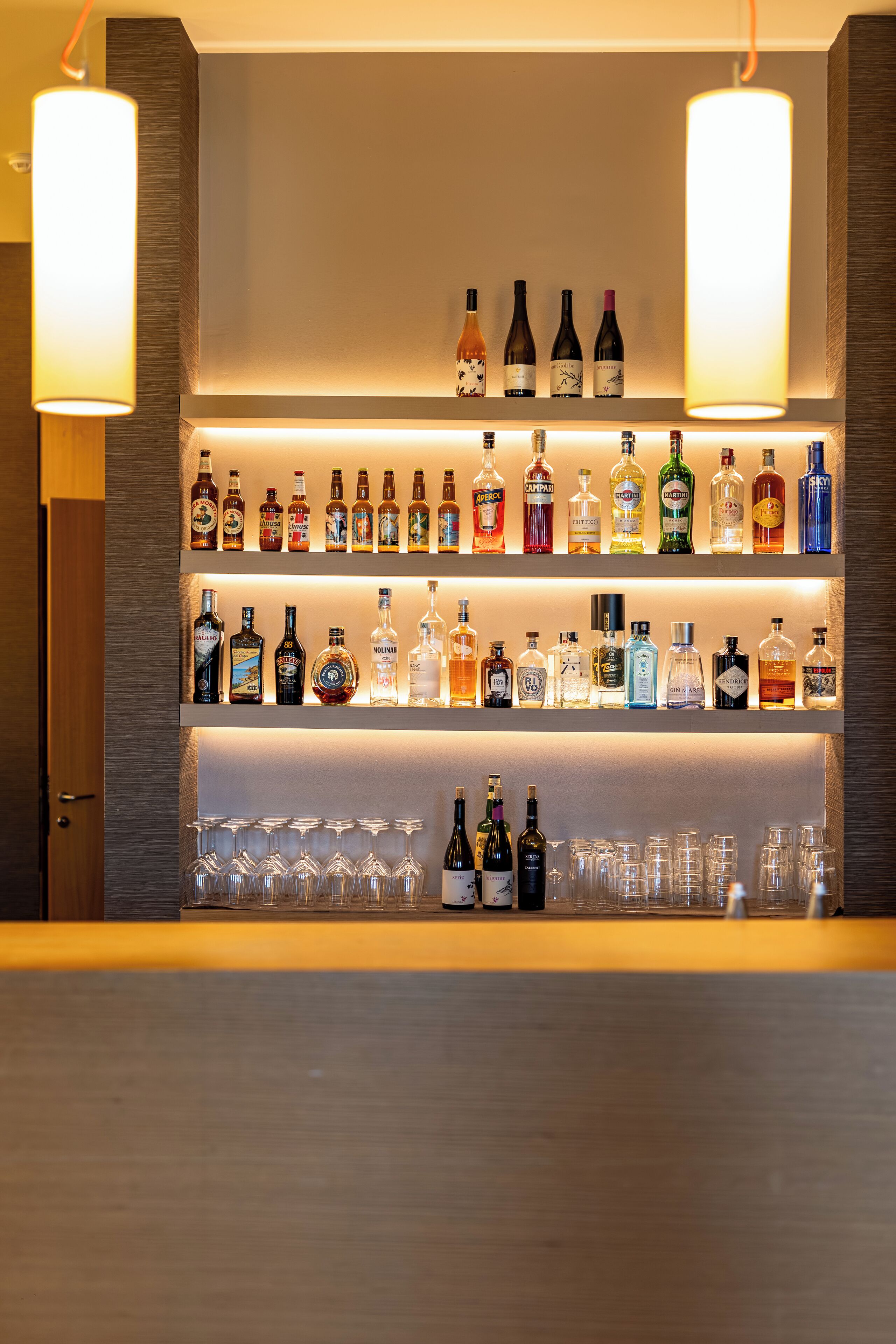 A bar area with shelves of liquor bottles and glasses.