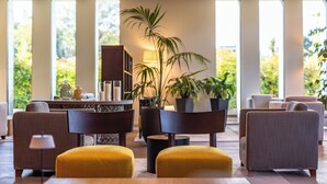 A modern living room with a sofa, armchairs, and a coffee table. There are potted plants and a lamp. - HSM Hotel San Martino (Garbagnate Monastero)