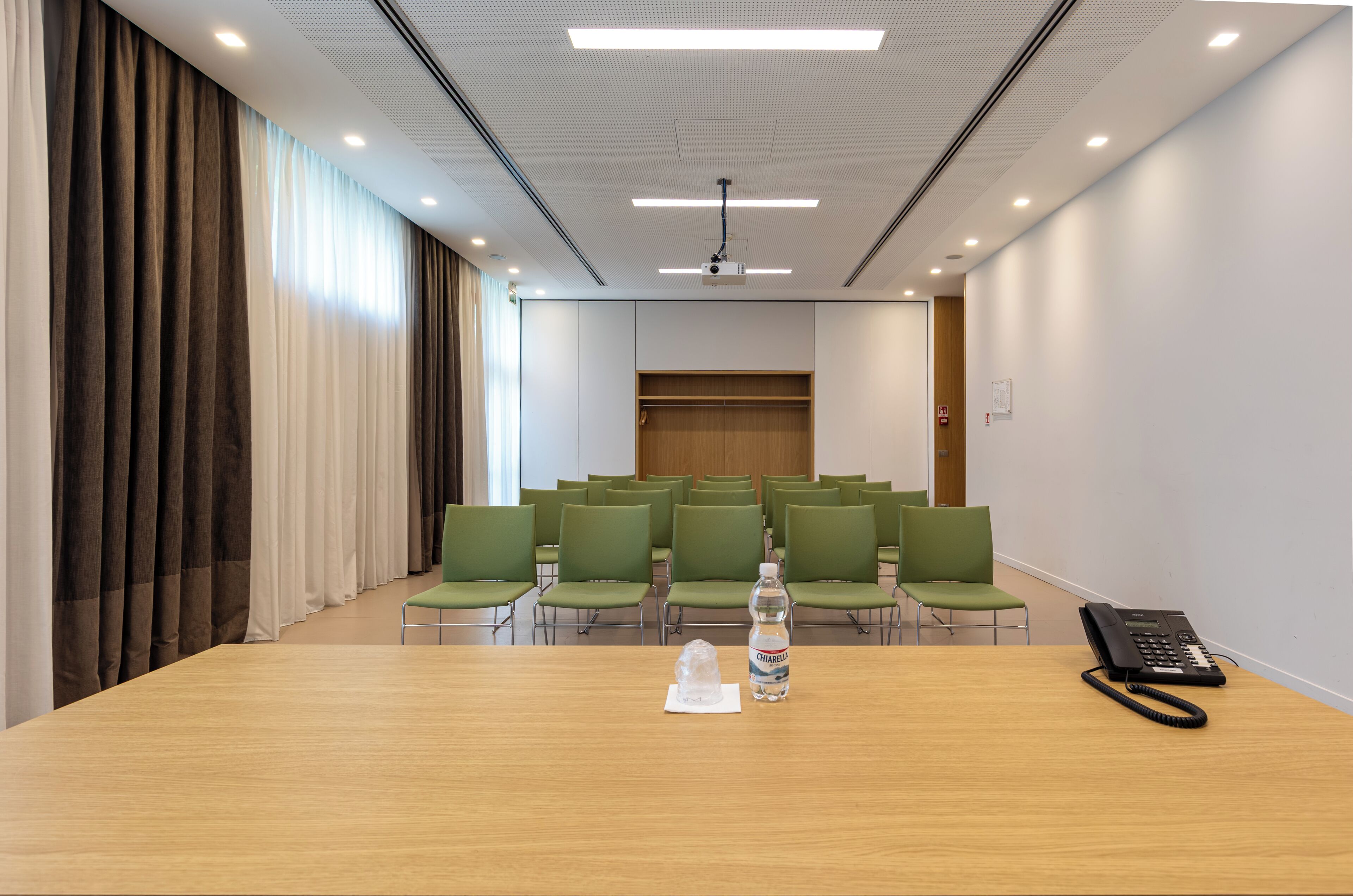 Uma sala de conferência com uma mesa de madeira, um projetor e um telefone.