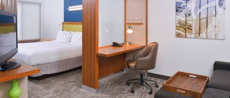 A hotel room with a bed, desk, chair, and a sofa.
