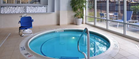 An indoor swimming pool with a 3 FT depth marker, a wheelchair-accessible chair, a potted plant, and a view of the outside through large windows.