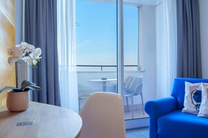 Habitación de hotel con balcón, una mesa con un código QR, un sofá azul y una orquídea en maceta.