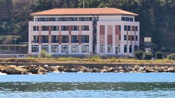 A multi-story building with a flat roof, located near a body of water.