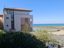 Un edificio moderno con balcón con vistas a una playa y al mar.