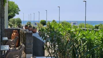 An outdoor seating area with stone walls, potted plants, and a view of the sea.