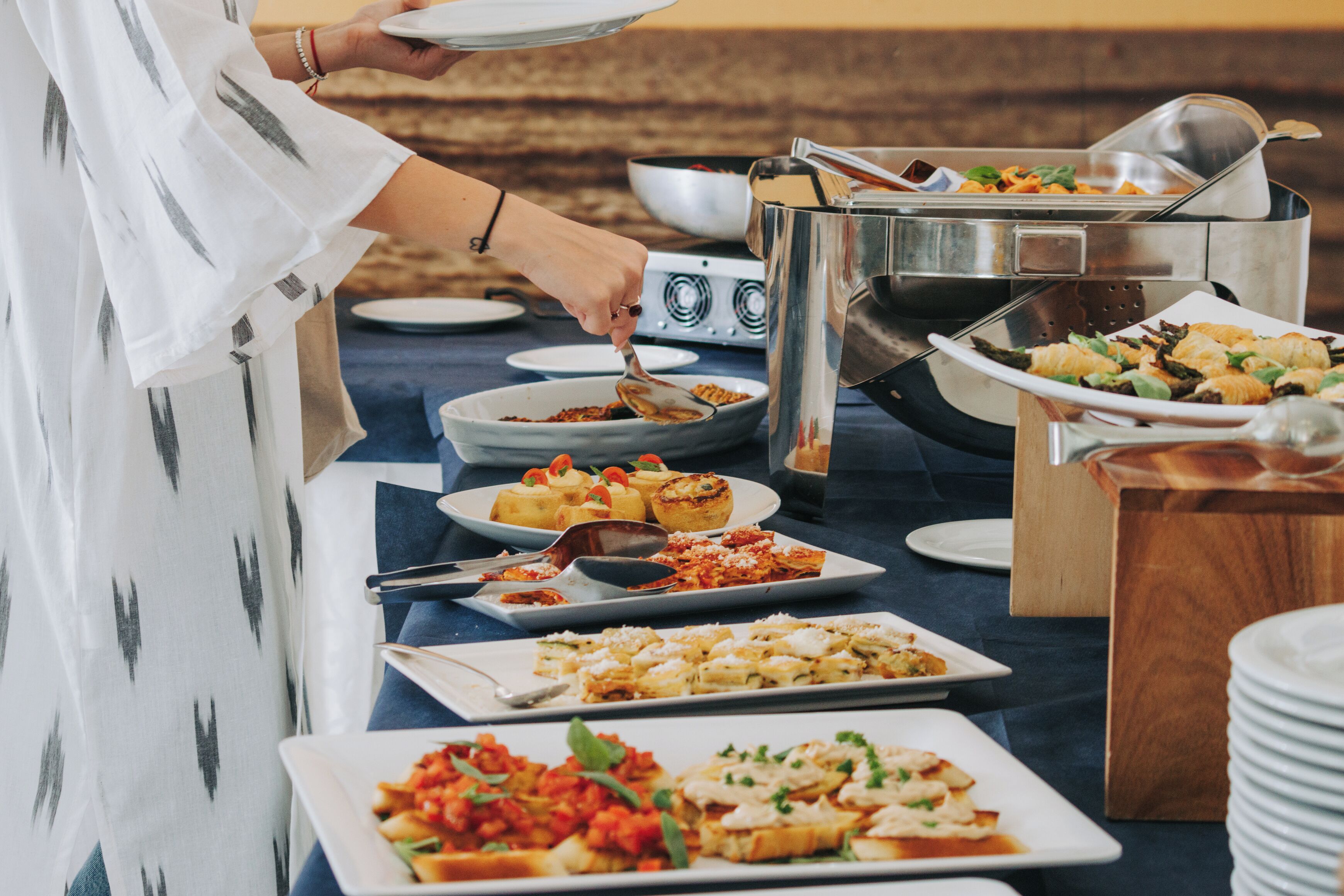 Un buffet con diversi piatti, tra cui pasta, insalate e pane, disposto su un tavolo.