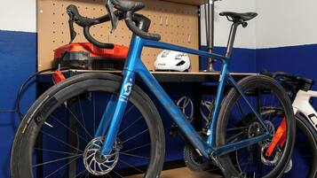 A bicycle parked in a room with a pegboard wall, a pair of sneakers on the floor, and a helmet on the wall.