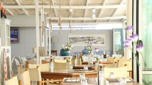 A restaurant with wooden tables and chairs, hanging decorations, and a view of the ocean. - Fantini Club Hotel  (Cervia)