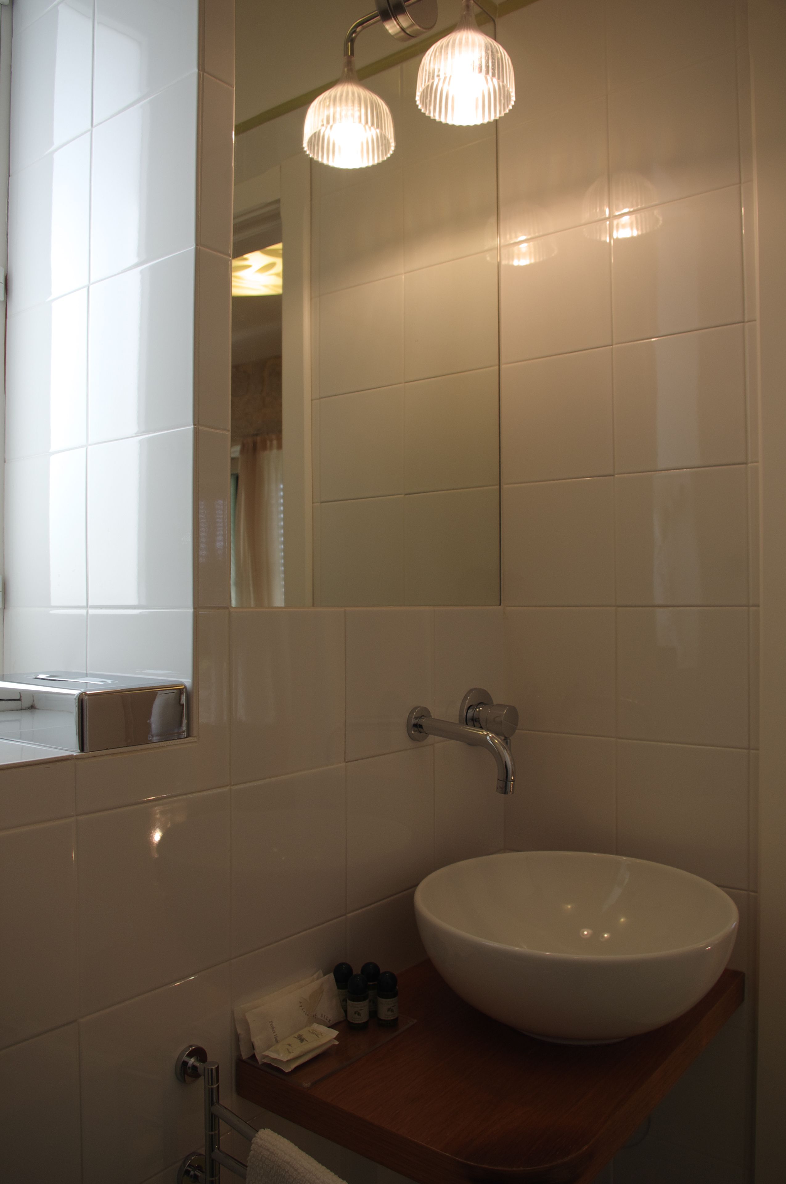 A bathroom with a white sink, a wooden countertop, and a mirror.