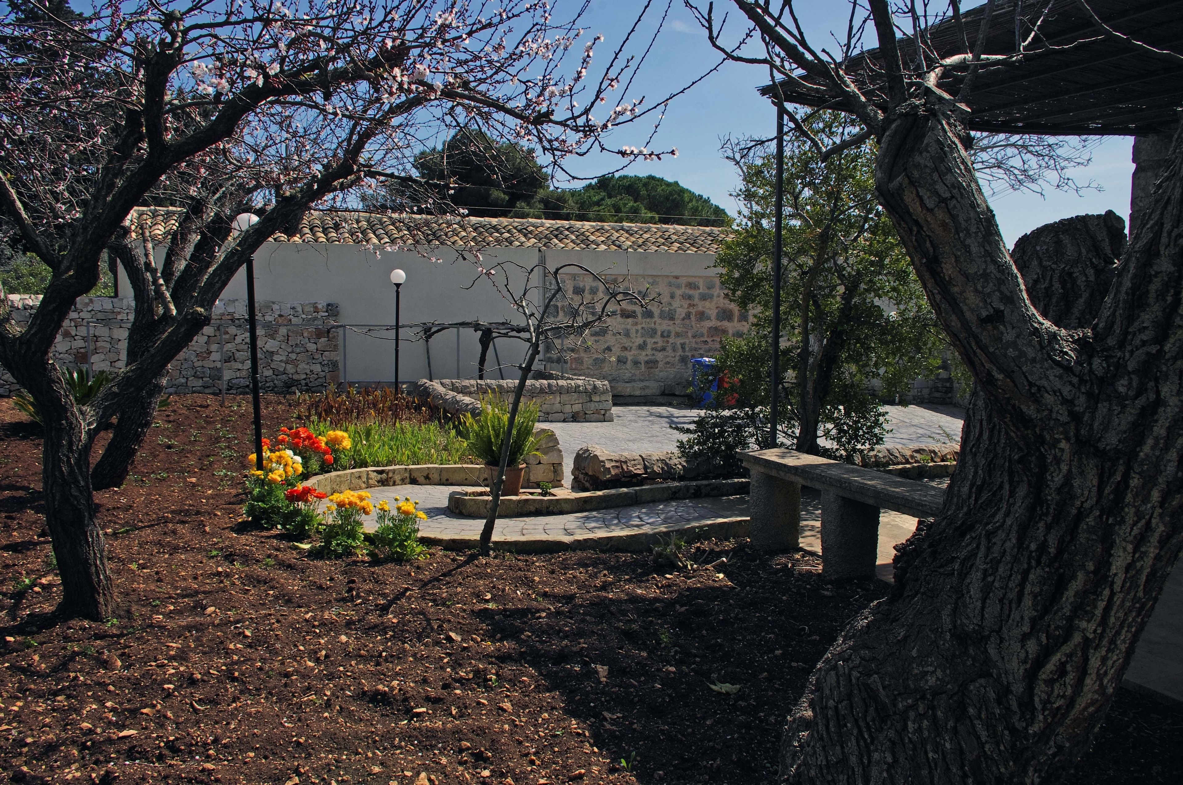 A garden with a stone wall, a bench, and flowering plants.
