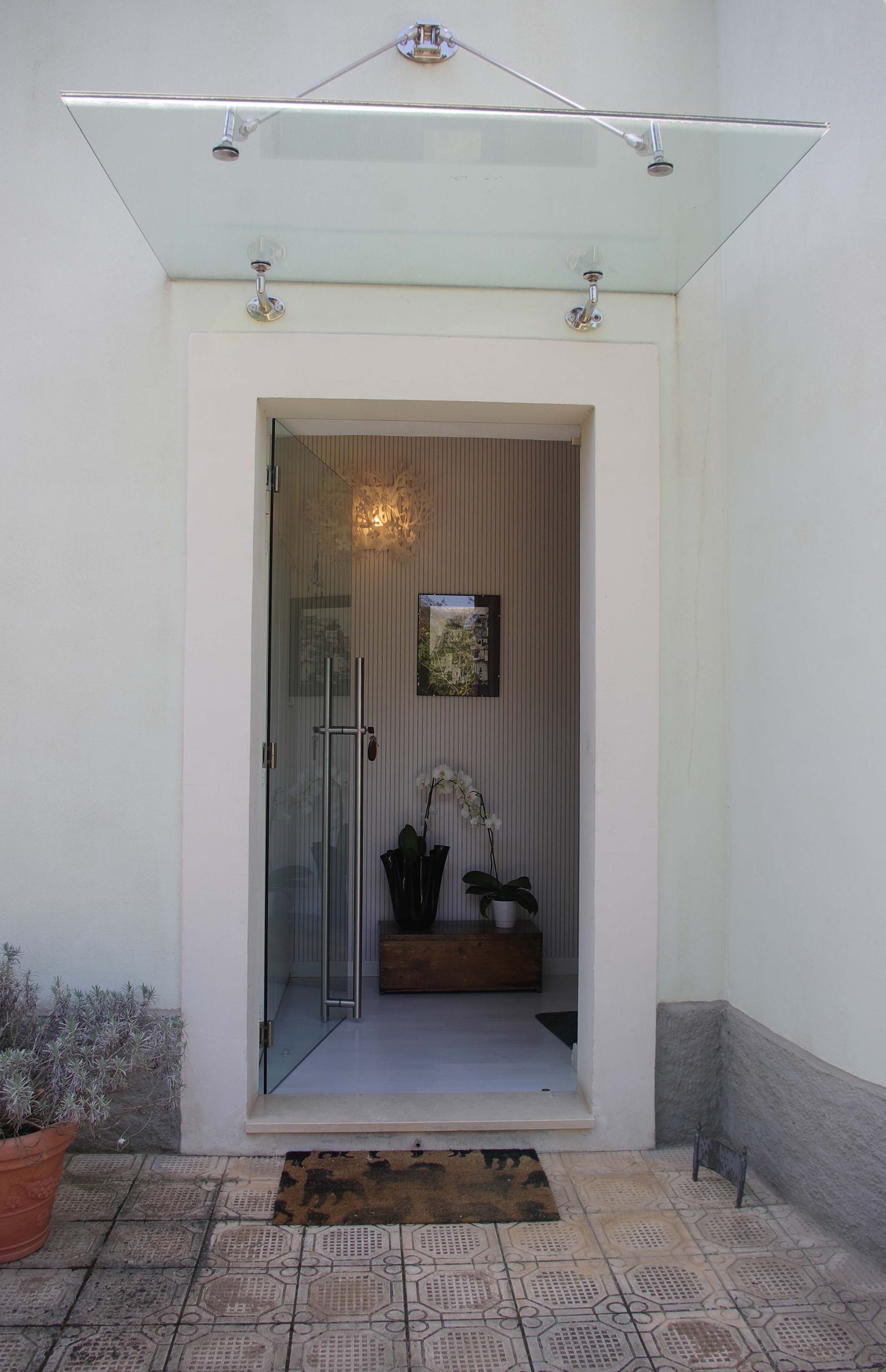 A modern entrance with a glass door, a small indoor garden, and a tiled floor.