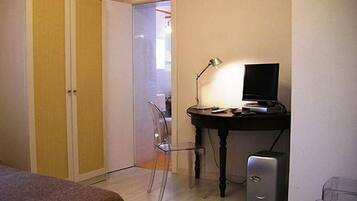 Een kleine kamer met een bureau, een stoel, een computer en een kledingkast.