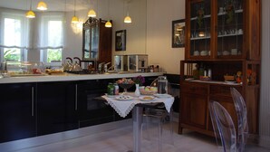 Una cocina moderna con armarios negros, un mueble de madera con puertas de cristal y una zona de comedor con una mesa para dos.
