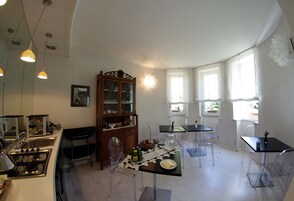 A modern kitchen with a dining area, featuring a stove, sink, and a dining table with chairs.