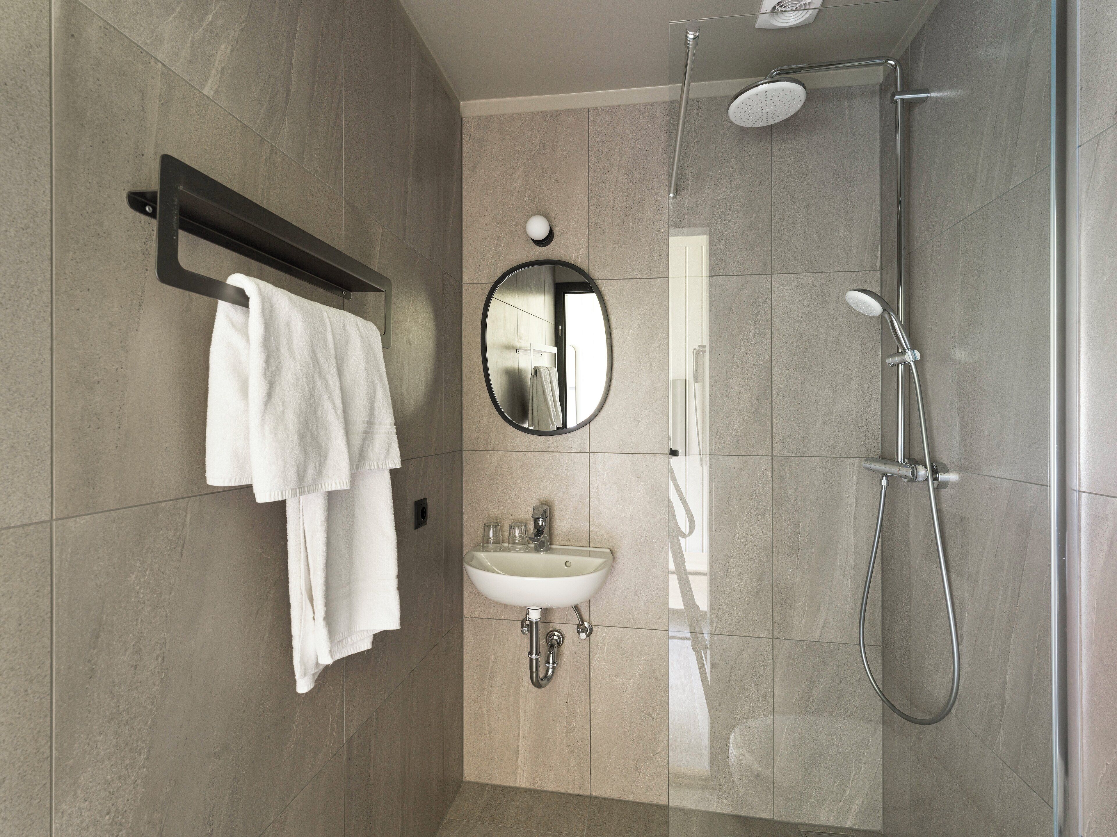 Un baño moderno con ducha, lavabo y espejo.