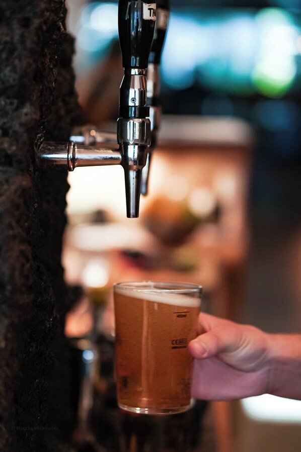 A hand holding a glass of beer near a beer tap. - Hotel Katla by Keahotels (Vik I Myrdal)