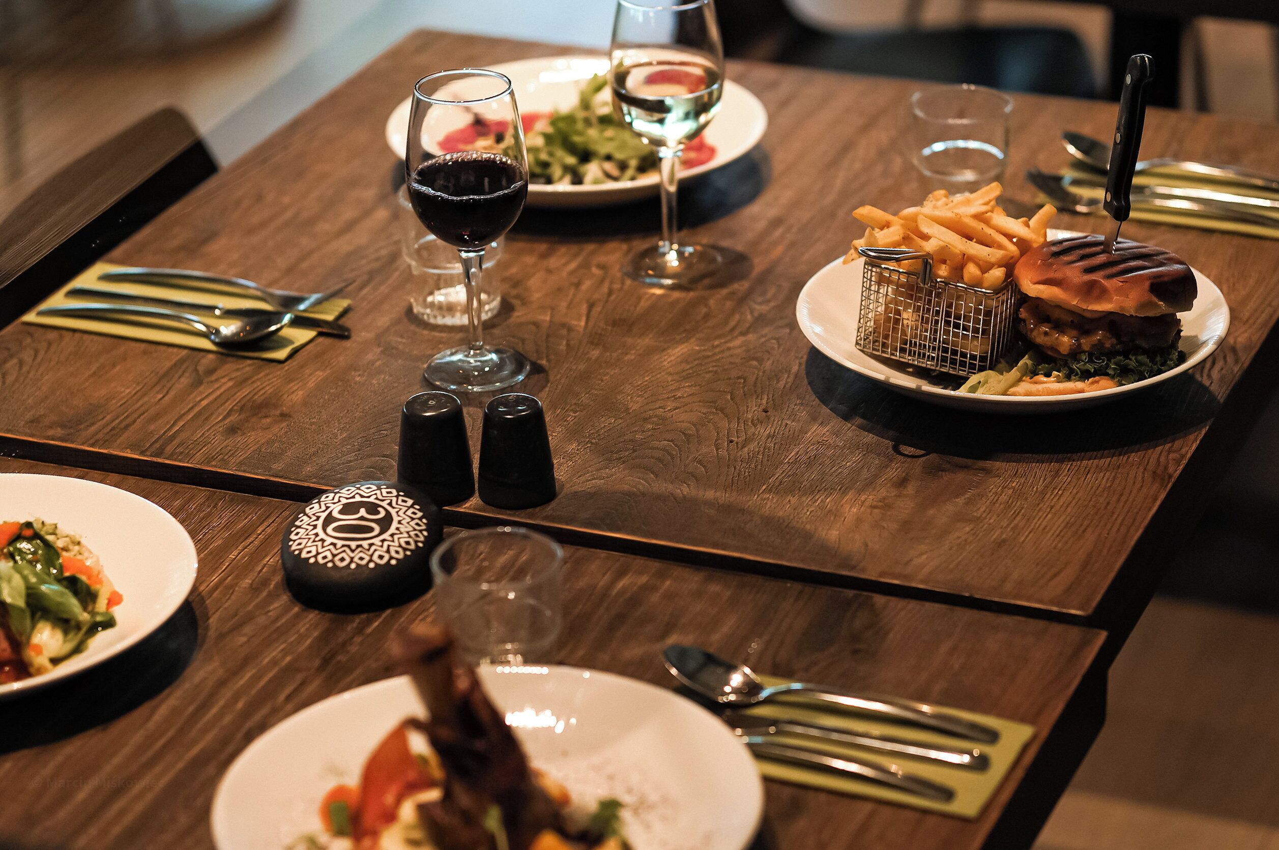 A dining table with plates of food, glasses of wine, and cutlery.
