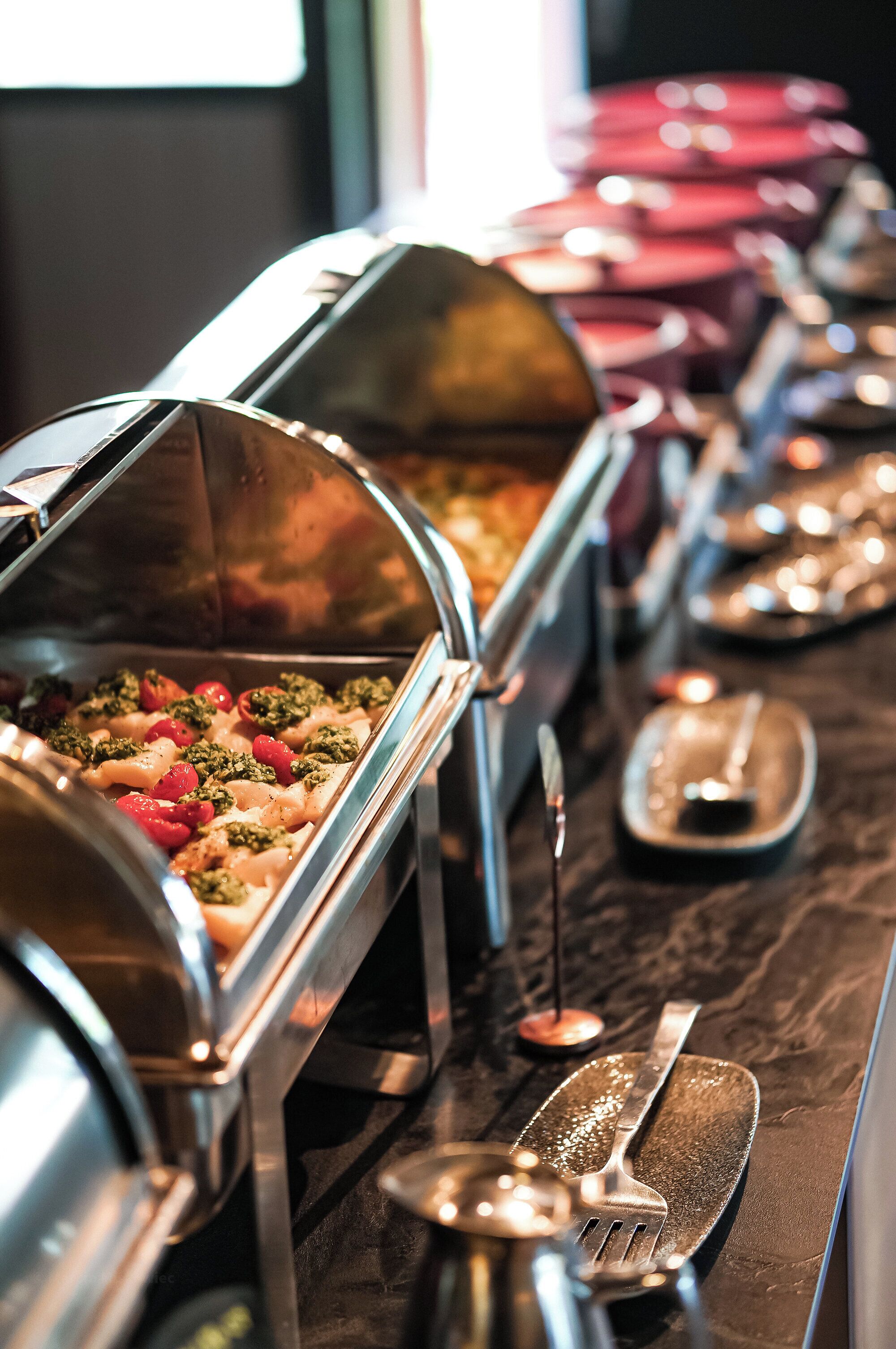 Ein Buffet mit verschiedenen Speisenausgabestationen und Besteck.