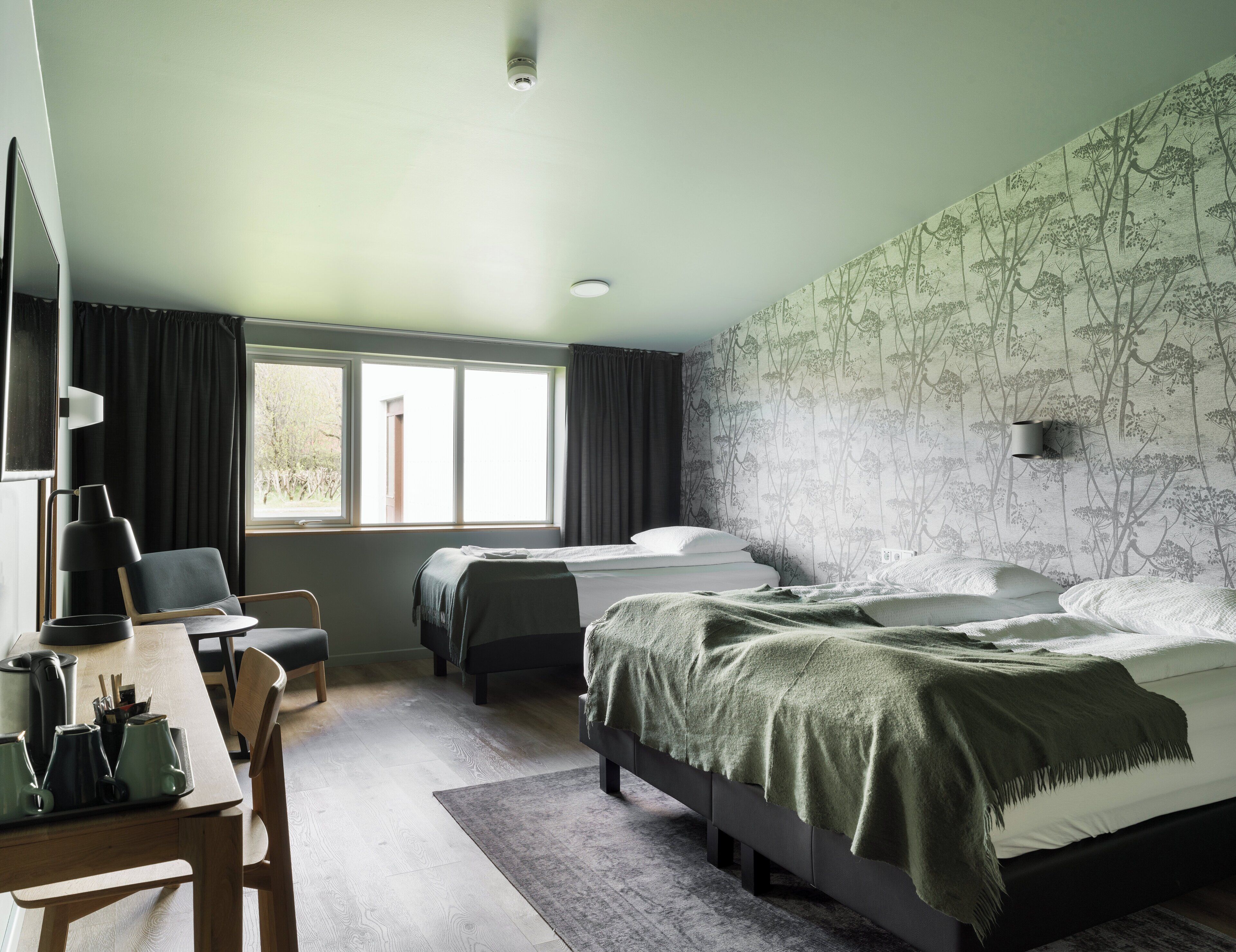 Une chambre avec deux lits, un bureau, une chaise et une fenêtre.