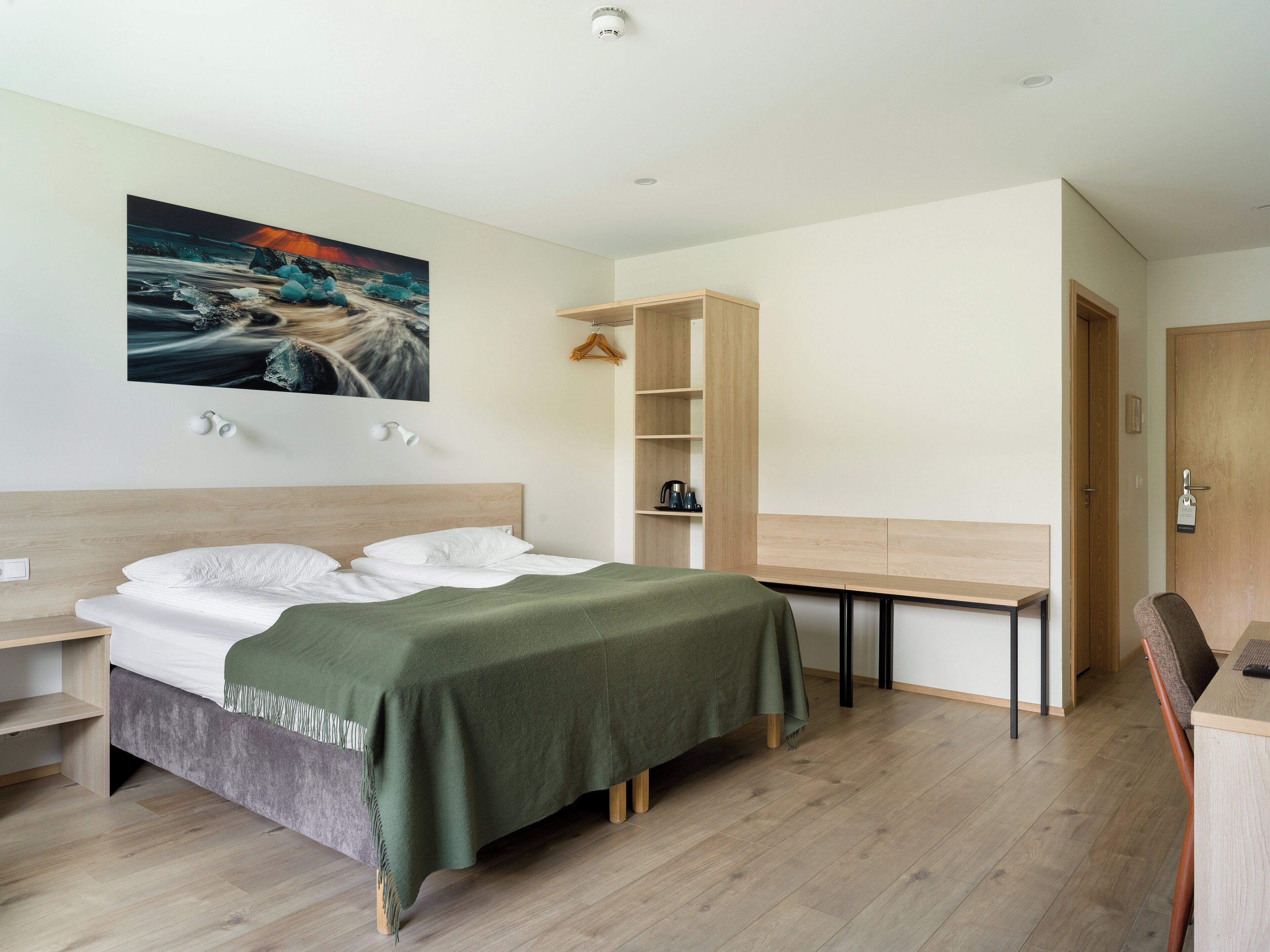 A modern bedroom with a bed, a desk, and a wardrobe.