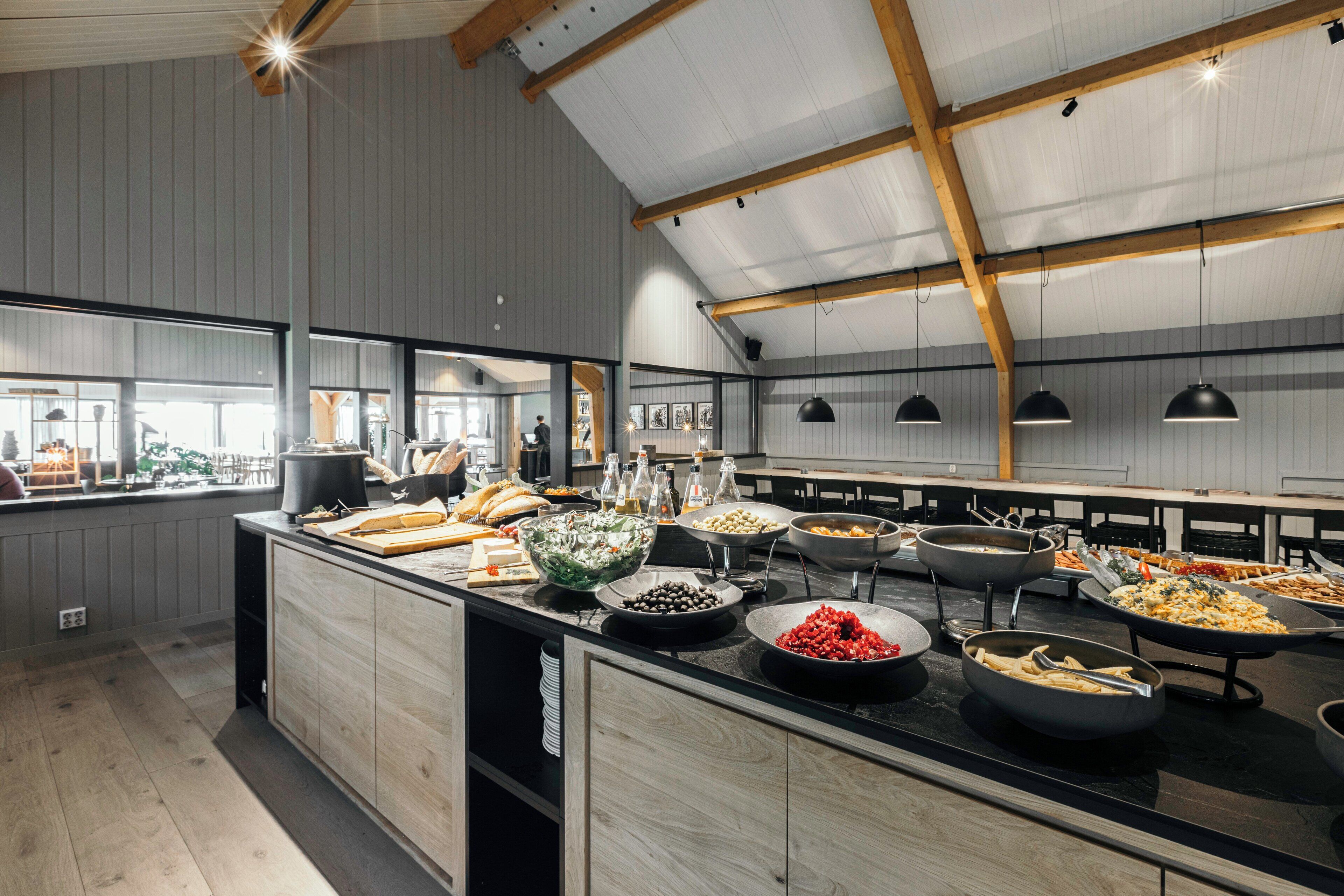 Een buffetopstelling met diverse gerechten en een houten plafondconstructie.