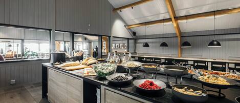 Een buffetopstelling met diverse gerechten en een houten plafondconstructie.