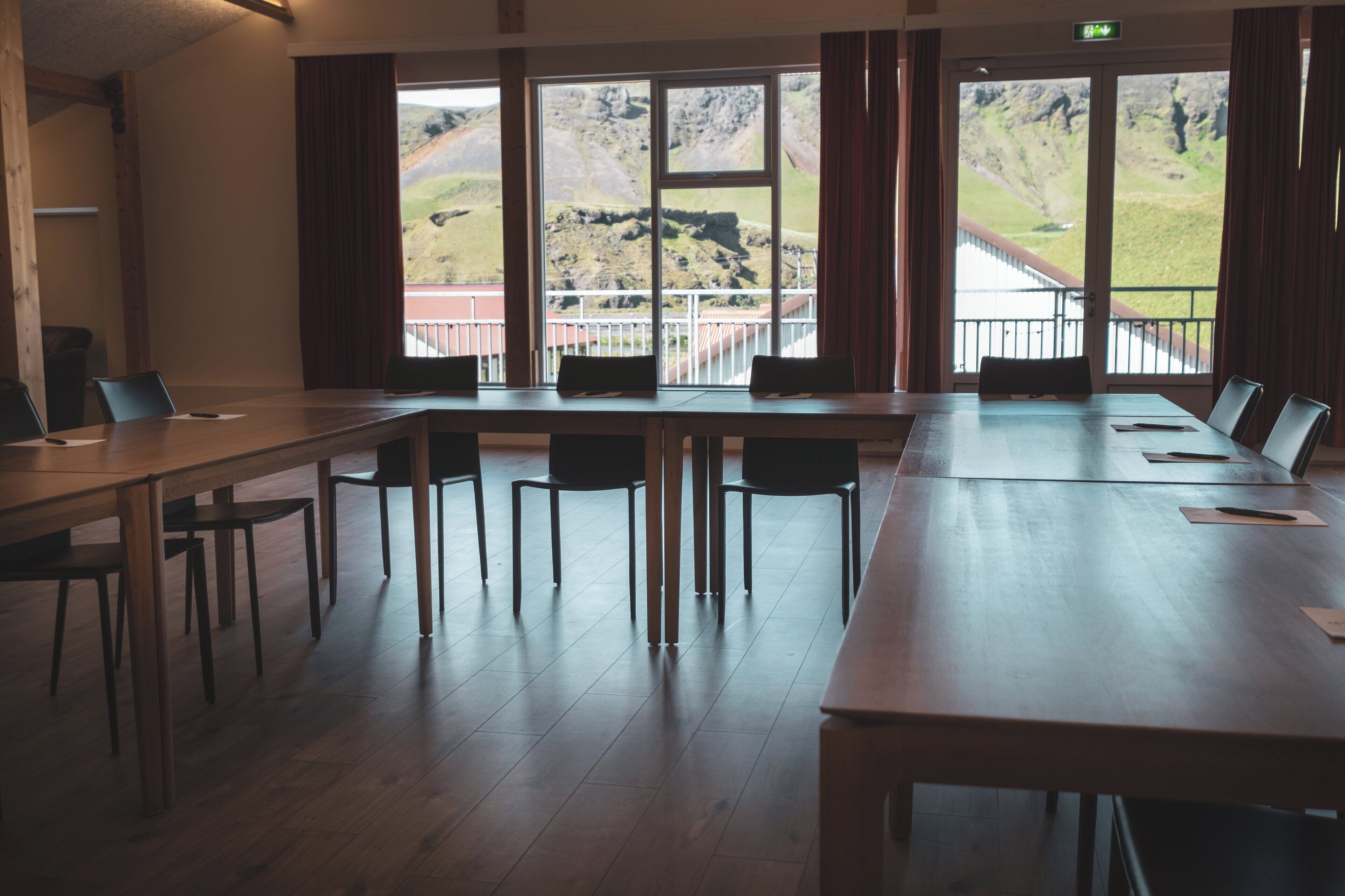 Un salón de conferencias con una larga mesa y sillas, ventanas amplias que ofrecen vistas a un paisaje montañoso.