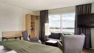 Relax in this serene space with a large bed, flat-screen TV, and seating area overlooking a body of water.
