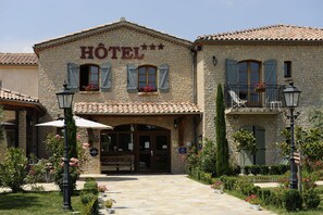 A stone building with a sign reading "HOTEL" and a balcony with a railing.