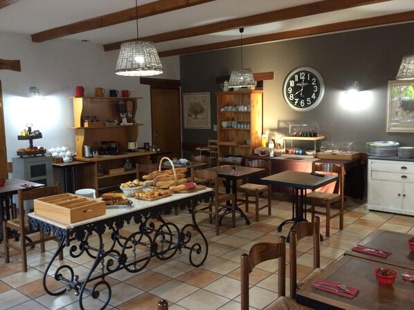 A cozy dining area with wooden furniture, a buffet table with food, and a clock on the wall. - Logis Hotel Le Mas de Mon Père (Saint-Jean-le-Centenier)