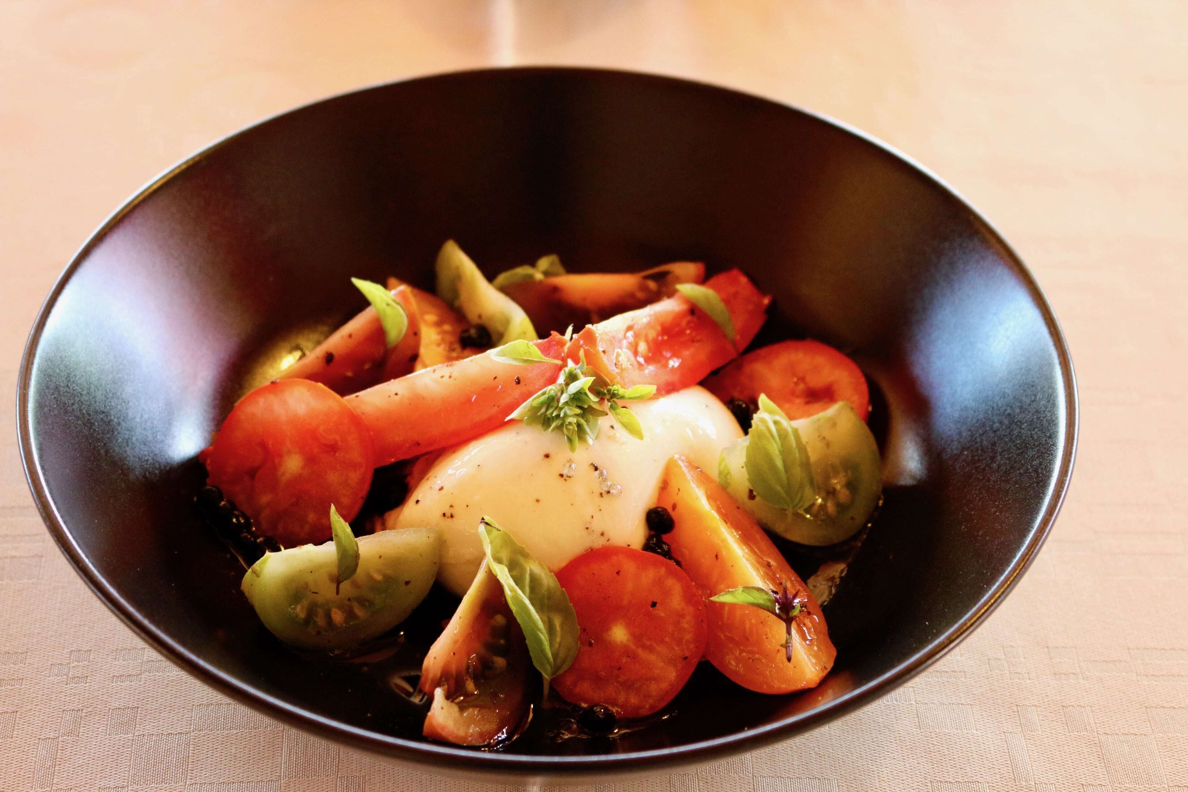 A bowl of food with tomatoes and basil.