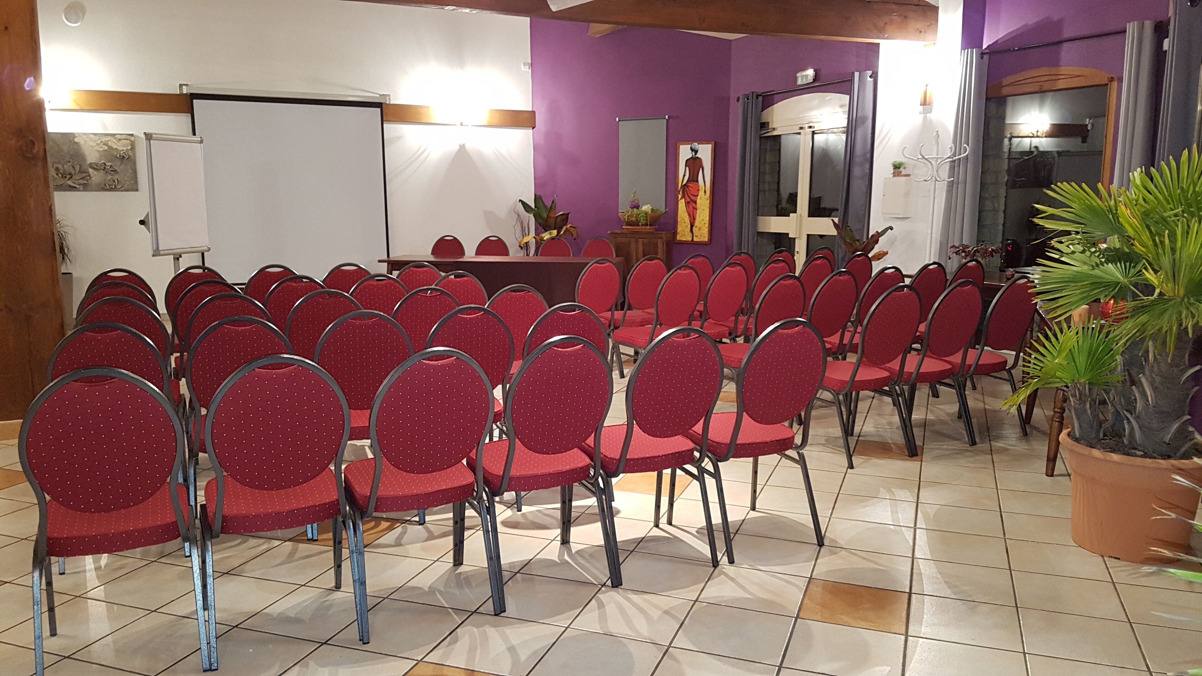 A conference room with red chairs arranged in rows, a whiteboard, and a podium.