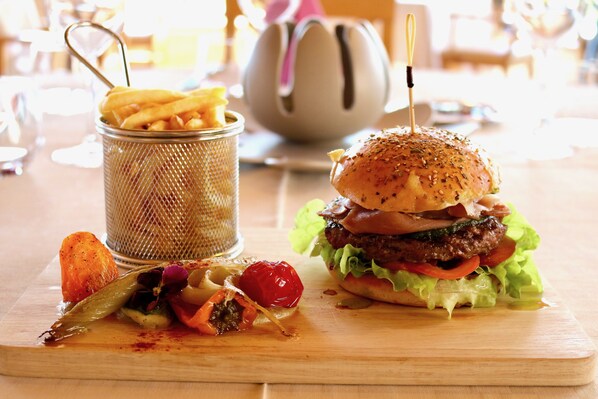 Una comida con una hamburguesa, papas fritas y una bebida sobre una mesa de madera.
