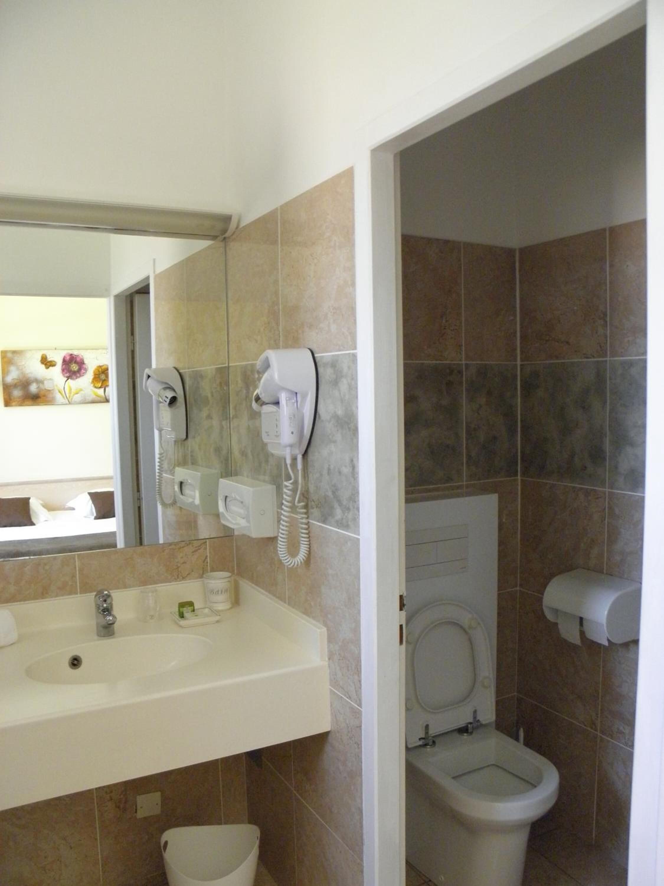 A bathroom with a sink, toilet, and bidet, featuring a telephone and a hand dryer.
