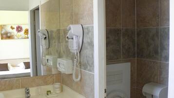 A bathroom with a sink, toilet, and bidet, featuring a telephone and a hand dryer.