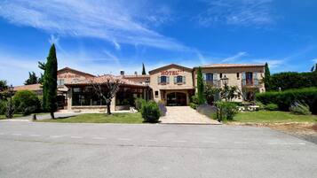 A hotel with a central entrance, multiple windows, and a tiled roof.