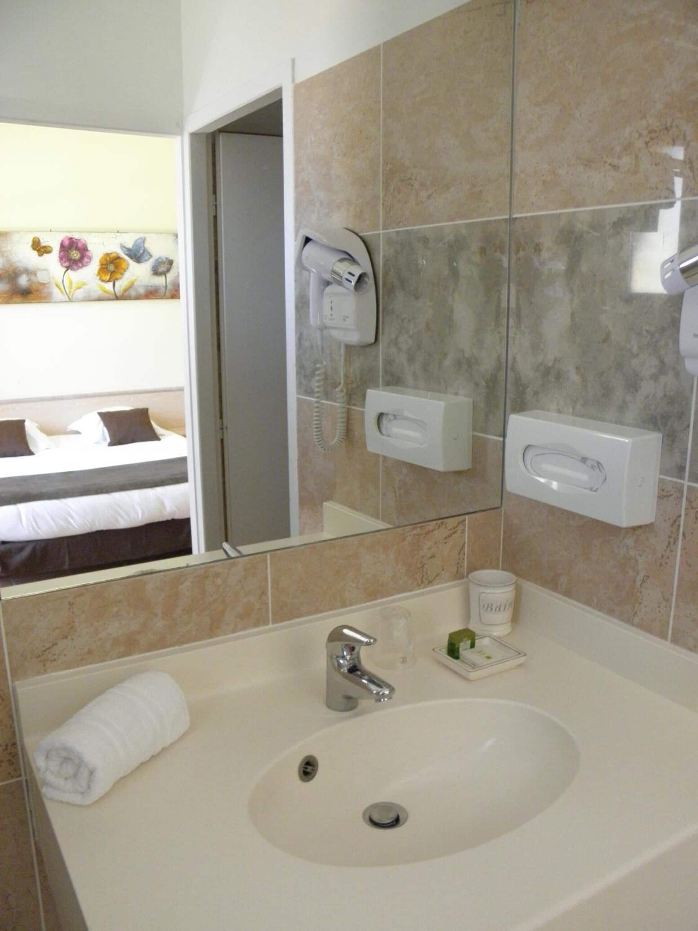 A hotel bathroom with a sink, mirror, and towel rack.