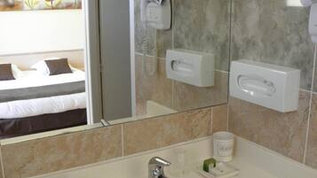 A hotel bathroom with a sink, mirror, and towel rack.