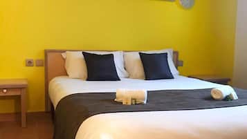 A hotel room with a bed, a nightstand, and a painting on the wall.