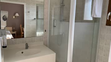 A modern bathroom with a glass-enclosed shower, a white sink, and a large mirror.