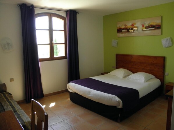 Un dormitorio con cama, ventana con cortinas, un cuadro en la pared y una silla.