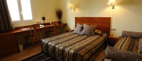 A bedroom with a bed, a desk, and a chair. There are two bedside lamps and a window with curtains.