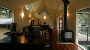 A modern interior with a fireplace, wooden flooring, and a view of the outdoors.