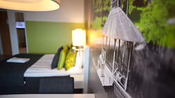 Una habitación de hotel con cama, escritorio, lámpara y un mural en la pared.