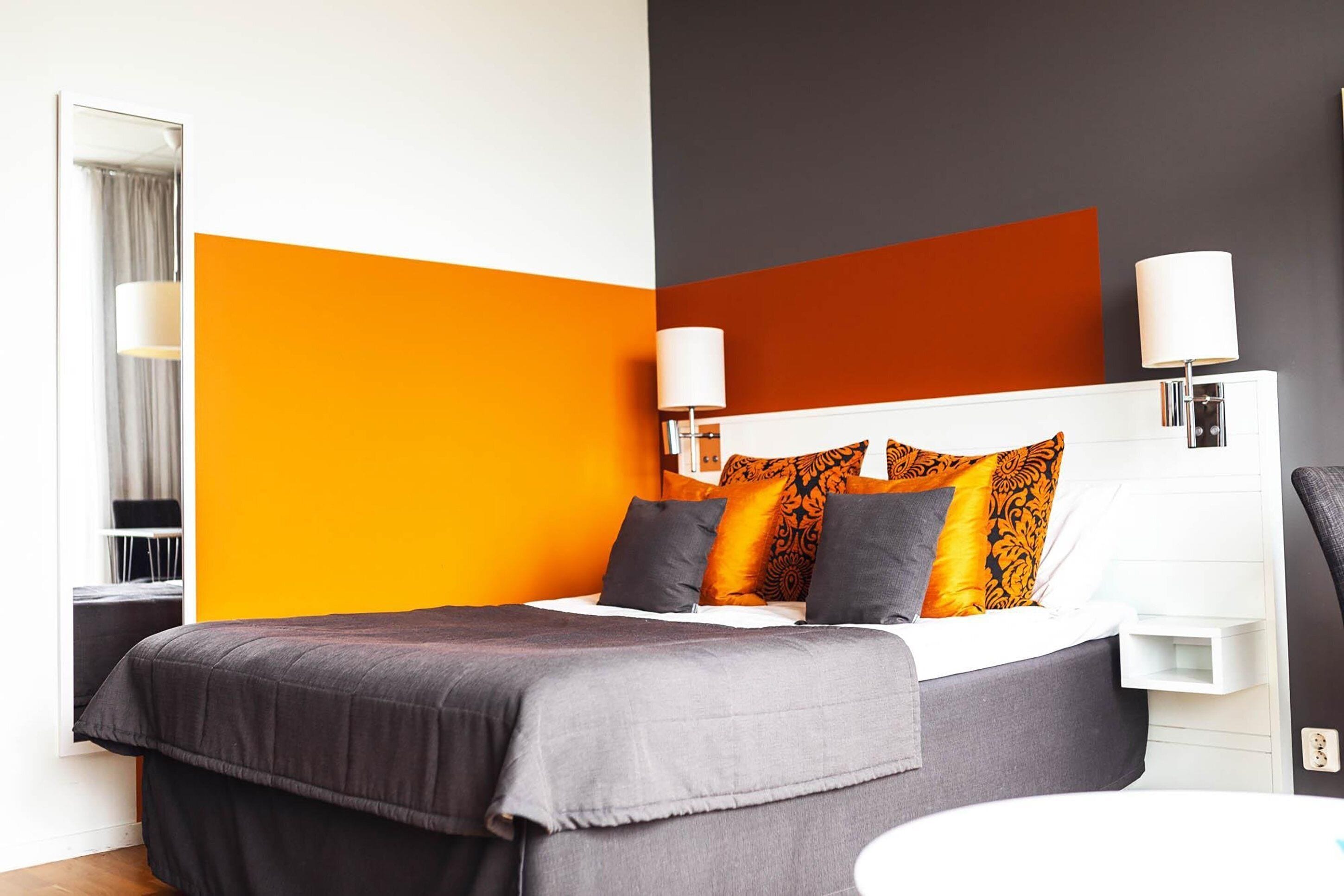 Una habitación de hotel moderna con una cama, lámparas de noche y una mesita de noche blanca.